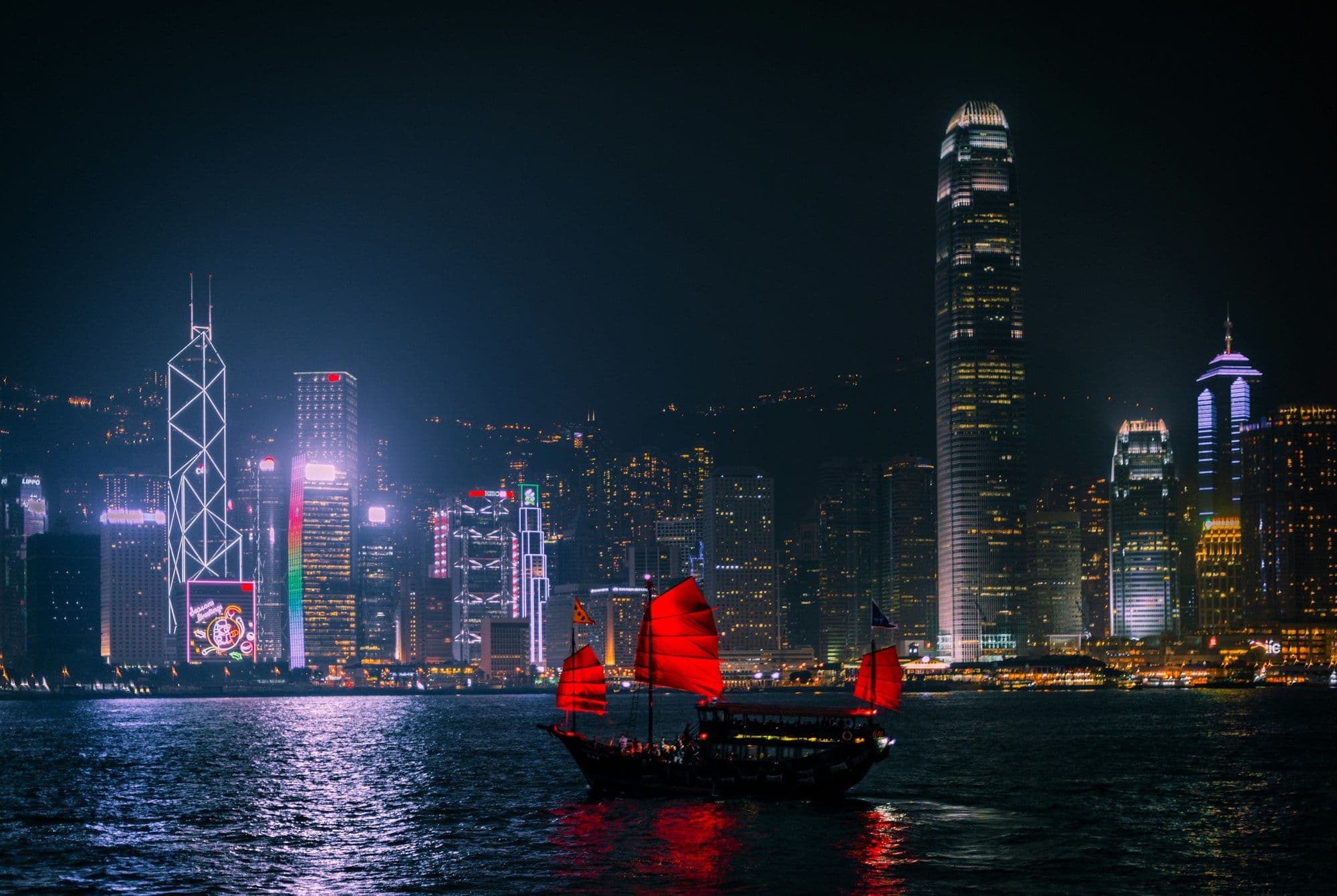 Traditional junk boat with red sails on Victoria Harbour, Hong Kong, at night